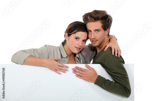 Photo: Couple stood with blank poster Couple stood with blank poster