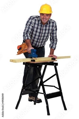 Photo: Man smoothing plank of wood with sander Man smoothing plank of wood with sander
