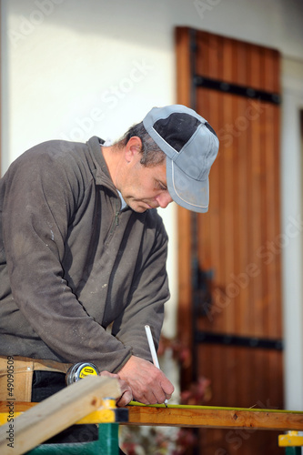 Photo: Man marking plank before cutting it Man marking plank before cutting it
