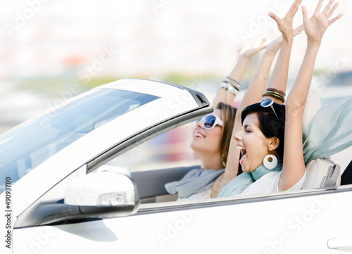 Photo: Female friends driving cabriolet with the hands up Female friends driving cabriolet with the hands up