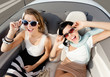 Photo: Top view of happy women with sunglasses sitting in the cabriolet Top view of happy women with sunglasses sitting in the cabriolet