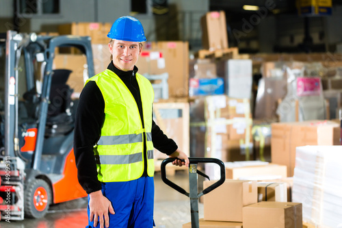 Photo: Storeman with mover at warehouse of forwarding Storeman with mover at warehouse of forwarding
