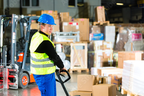 Photo: Storeman with mover at warehouse of forwarding Storeman with mover at warehouse of forwarding