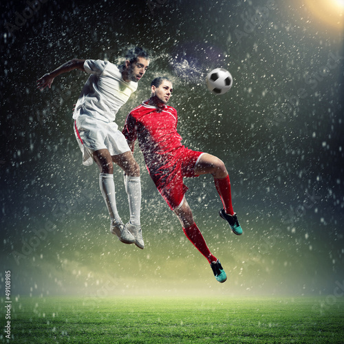 Photo: two football players striking the ball two football players striking the ball