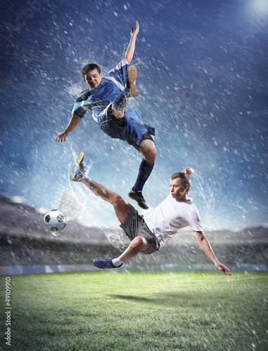 Photo: two football players striking the ball two football players striking the ball