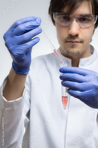 Photo: Chemiker träufelt eine rote Flüssigkeit in ein Reagenzglas Chemiker träufelt eine rote Flüssigkeit in ein Reagenzglas