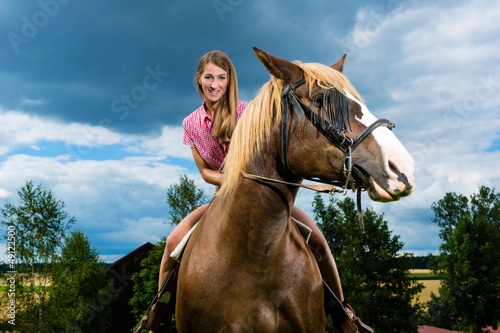 Photo: Young woman riding the horses on the meadow Young woman riding the horses on the meadow