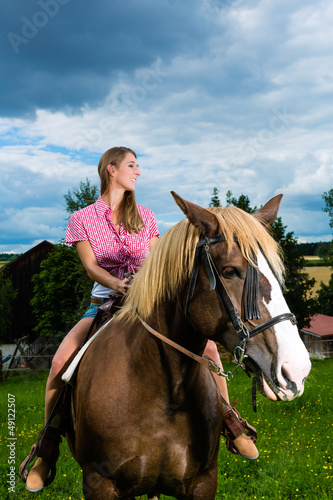 Photo: Young woman riding the horses on the meadow Young woman riding the horses on the meadow