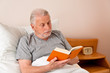 Senior im Altenheim beim Buch lesen im Bett