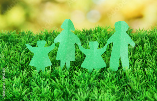 Photo: Paper people on green grass on bright background Paper people on green grass on bright background