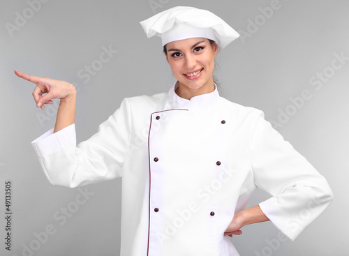 Photo: Portrait of young woman chef on grey background Portrait of young woman chef on grey background
