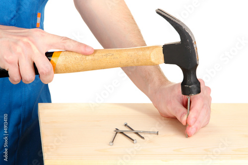 Photo: Builder hammering nails into board isolated on white Builder hammering nails into board isolated on white