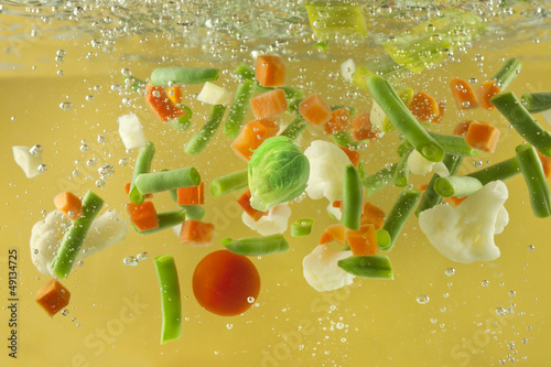 Photo: Vegetables splash in water soup cooking concept Vegetables splash in water soup cooking concept