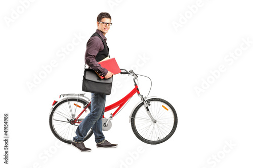 Photo: Full length portrait of a smiling student holding books and push Full length portrait of a smiling student holding books and push