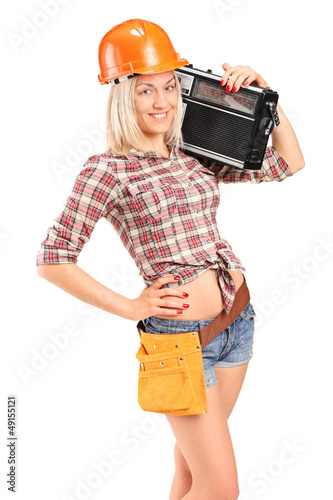 Photo: Smiling female worker with helmet listening to radio Smiling female worker with helmet listening to radio