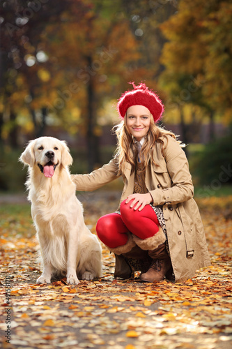 Photo: Smiling young woman posing with a labrador retriever out in a pa Smiling young woman posing with a labrador retriever out in a pa