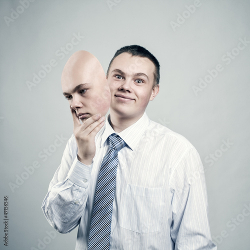 Photo: Businessman removes the mask from the face of a bad mood Businessman removes the mask from the face of a bad mood