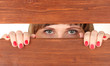 Photo: Female eyes looking through hole in wooden desk Female eyes looking through hole in wooden desk