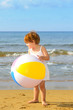 Photo: Toddler girl playing with her inflatable ball at beach Toddler girl playing with her inflatable ball at beach