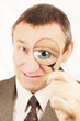 Angry man looks through a magnifying glass