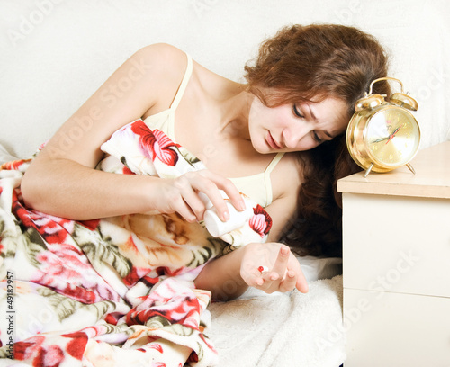 Photo: Unhappy woman takes sleeping pills for insomnia Unhappy woman takes sleeping pills for insomnia