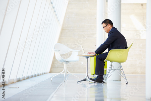 Photo: Businessman Working On Laptop At Table In Modern Office Businessman Working On Laptop At Table In Modern Office