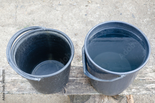 Photo: Two plastic buckets, one full, one empty Two plastic buckets, one full, one empty