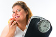 Obese woman with scale under arm and apple