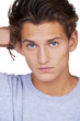 Serious young guy looking at you with his hand in his hair