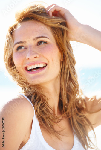 Photo: A lovely young blonde woman running her fingers through her hair A lovely young blonde woman running her fingers through her hair