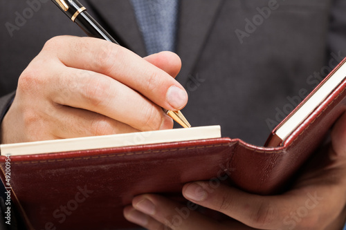 Photo: Businessman writing on his agenda Businessman writing on his agenda