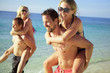 Photo: Two young guys piggybacking their girlfriends on the beach Two young guys piggybacking their girlfriends on the beach