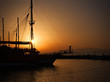 Sailing ship silhouetted against amber setting sun