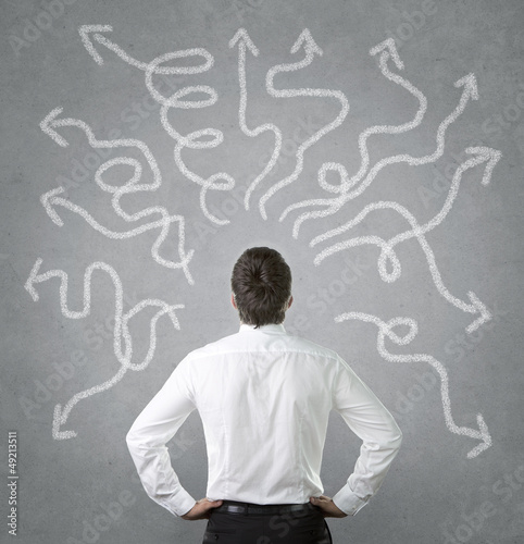 Photo: Confused businessman looking at many twisted arrows Confused businessman looking at many twisted arrows