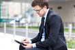 Young businessman using a tablet on a bench in the city