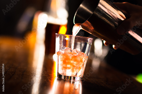 Photo: Hands of a bartender pouring a drink into a glass Hands of a bartender pouring a drink into a glass