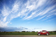 Foto: Red Volkswagen Beetle car on rural road. Red Volkswagen Beetle car on rural road.