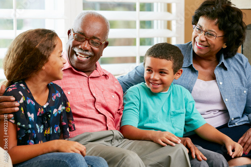 Photo: Grandparents With Grandchildren Sitting On Sofa And Talking Grandparents With Grandchildren Sitting On Sofa And Talking