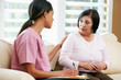 Nurse Discussing Records With Senior Female Patient at Home