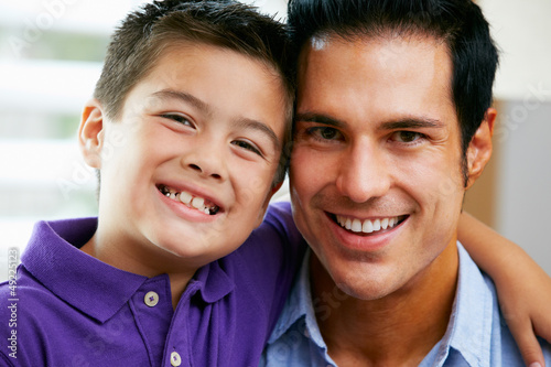 Photo: Portrait Of Father And Son Sitting On Sofa At Home Portrait Of Father And Son Sitting On Sofa At Home