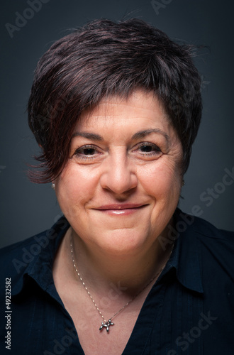 Photo: Middle age woman close up portrait on dark background. Middle age woman close up portrait on dark background.