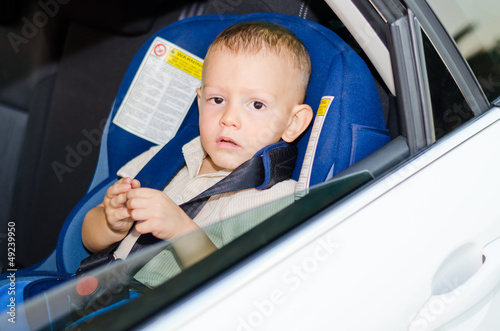 Photo: Little boy child safety seat sitting patiently back of car Little boy child safety seat sitting patiently back of car