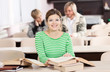 Cheerful young woman studying at desk with lots of books