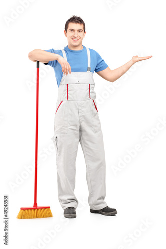Photo: Full length portrait of a male cleaner with a broom gesturing Full length portrait of a male cleaner with a broom gesturing
