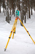 Electronic tacheometer on tripod in winter forest vertical view