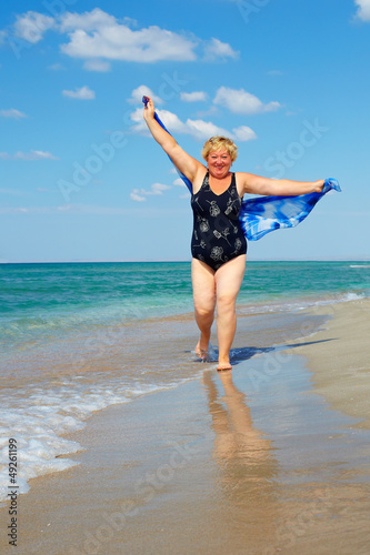 Photo: active mature woman running the beach active mature woman running the beach