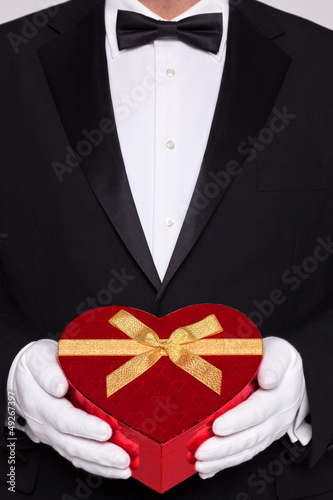 Photo: Man in black tie holding a heart shaped box of chocolates Man in black tie holding a heart shaped box of chocolates