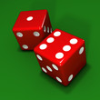 Two red dice on green background