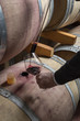 Italy, red wine pouring from a wooden barrel into a glass