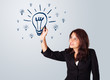 Woman drawing light bulb on whiteboard
